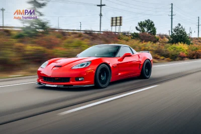 Red Corvette Z06 driving on a scenic highway showcasing its high performance and sleek sports car design