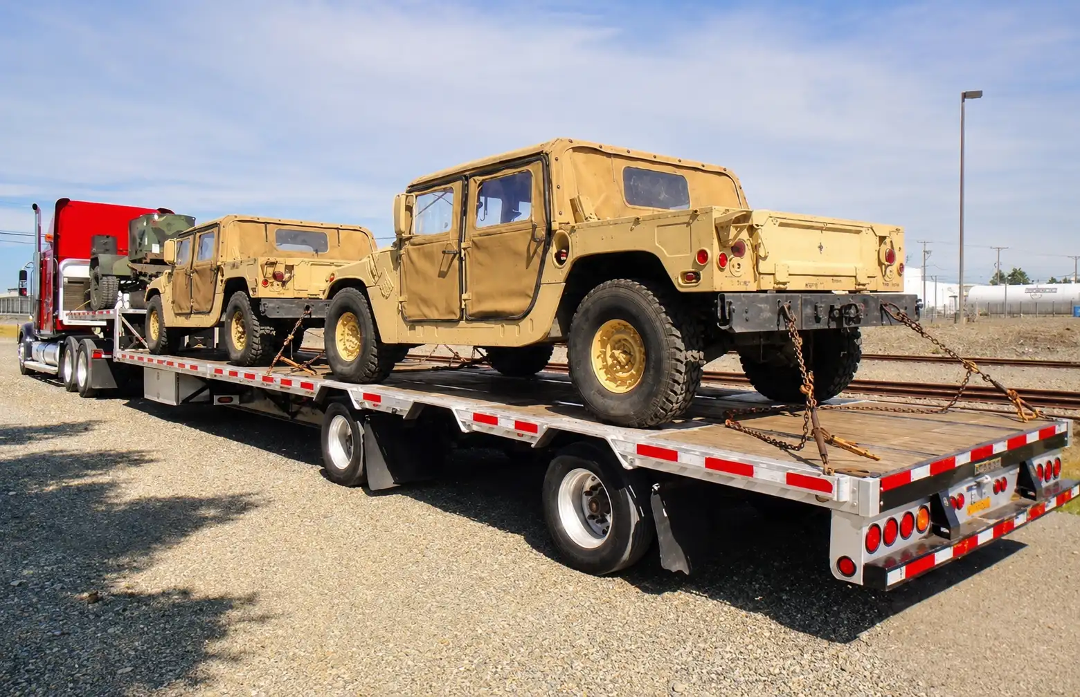 Two military Humvees secured on a flatbed trailer for transport.